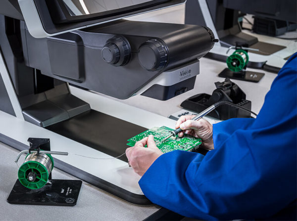 Hands of person soldering a PCB under magnification using DRV-Z1