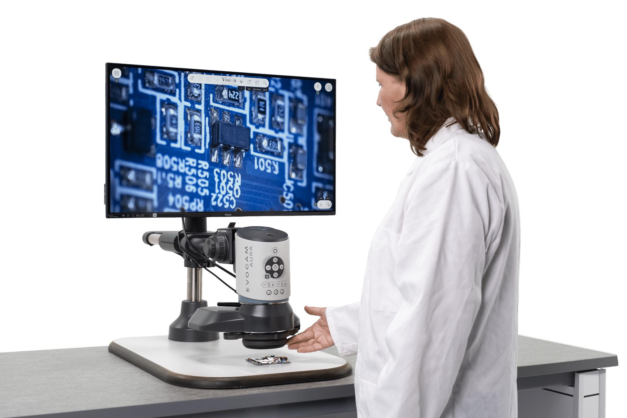 Quality engineer at an EVO Cam AURA digital inspection system, with a magnified printed circuit board shown on the monitor