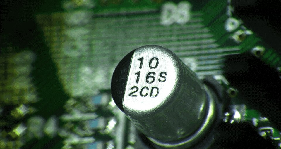 Close-up of a capacitor on a printed circuit board viewed under magnification
